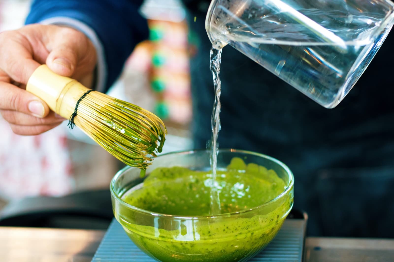 person pouring water into matcha tea
