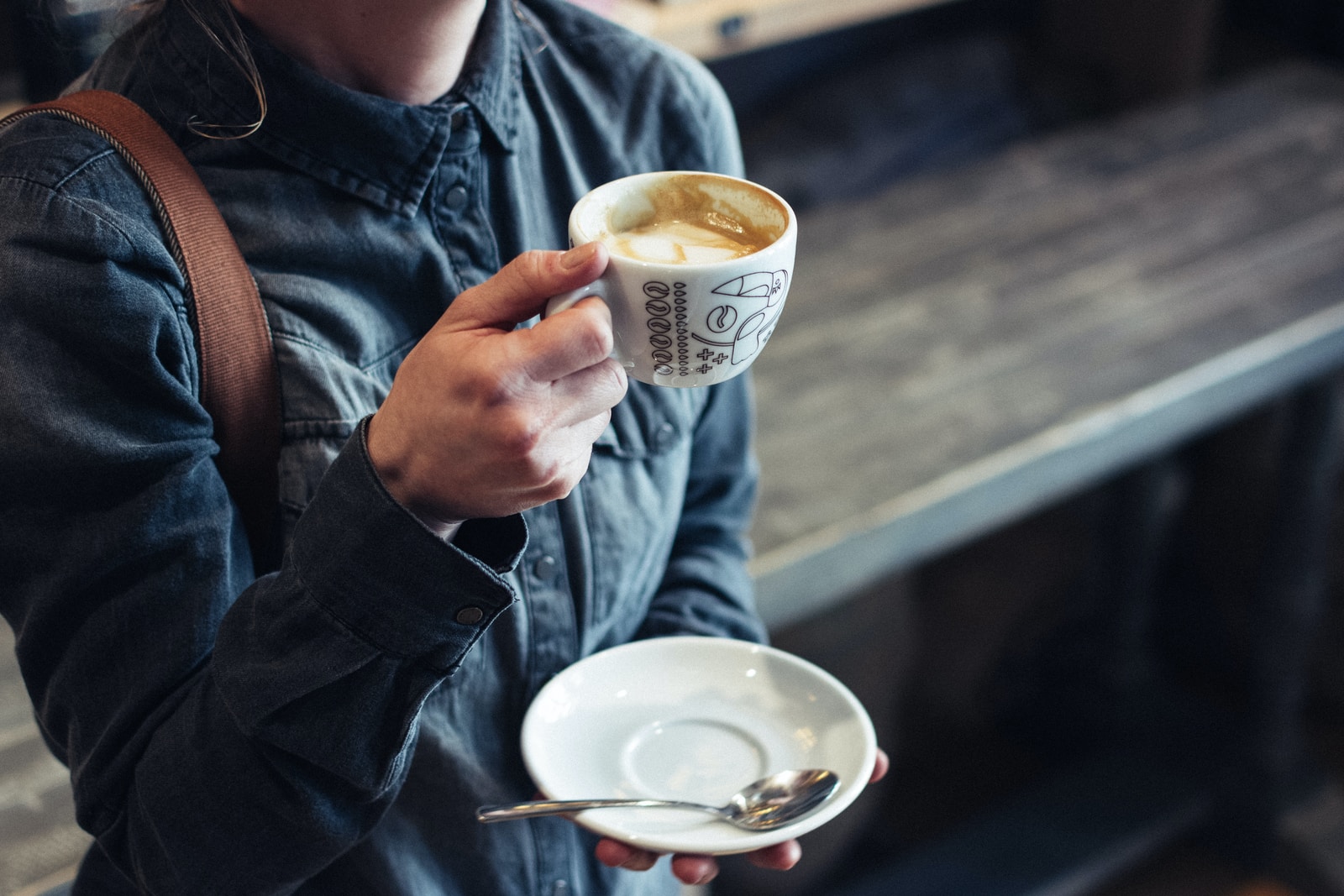 person holding cup of coffee and saucer