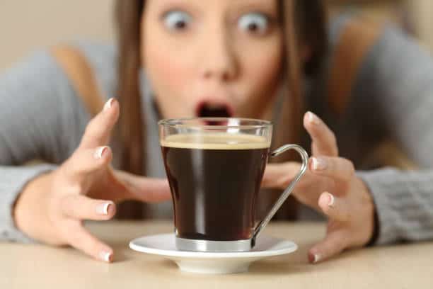Front view portrait of an amazed woman looking at coffee cup