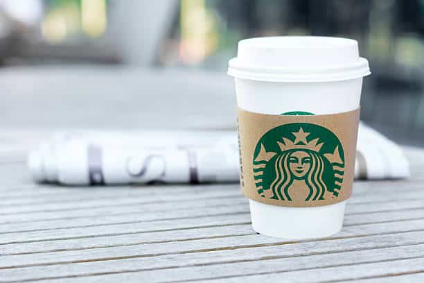 Bangkok, Thailand - Feb 26, 2015 : Starbucks coffee cup with newspaper on the table, Starbucks brand is one of the most world famous coffeehouse chains from USA.
