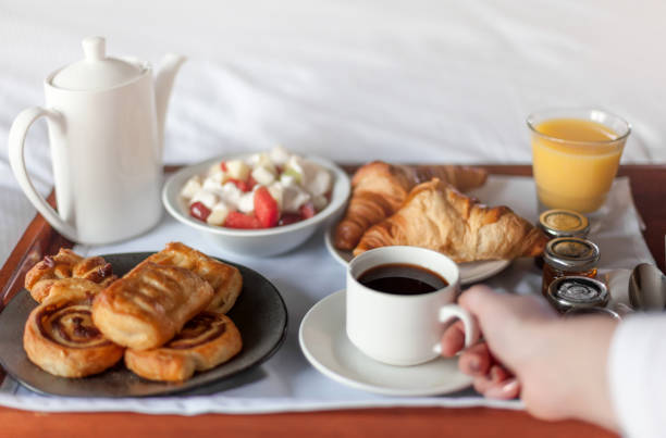 Bed breakfast with coffee cup, croissants and orange juice on white sheets