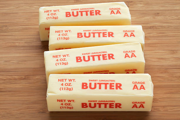 Four quarter pound sticks of sweet unsalted AA grade butter on a bamboo cutting board.