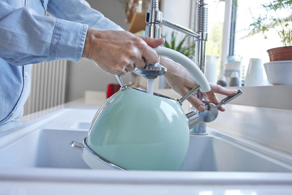 Close Up Of Woman Carefully Filling Kettle From Tap And Saving Water