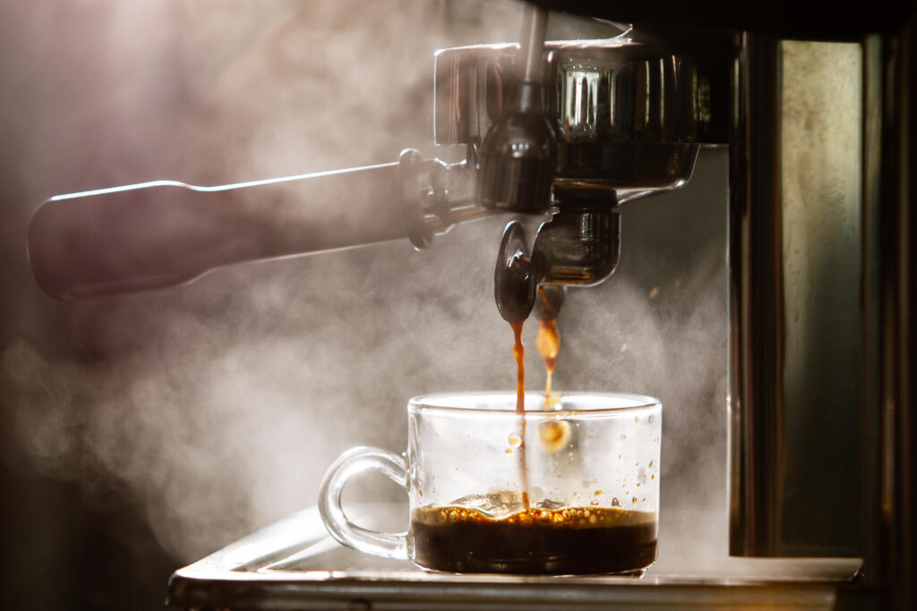 Barista brewing the espresso coffee by using high pressured espresso machine in a small coffee shop. Coffee machinery in coffee shop.