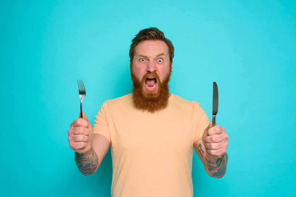 Hungry man is ready to eat with cutlery in hand